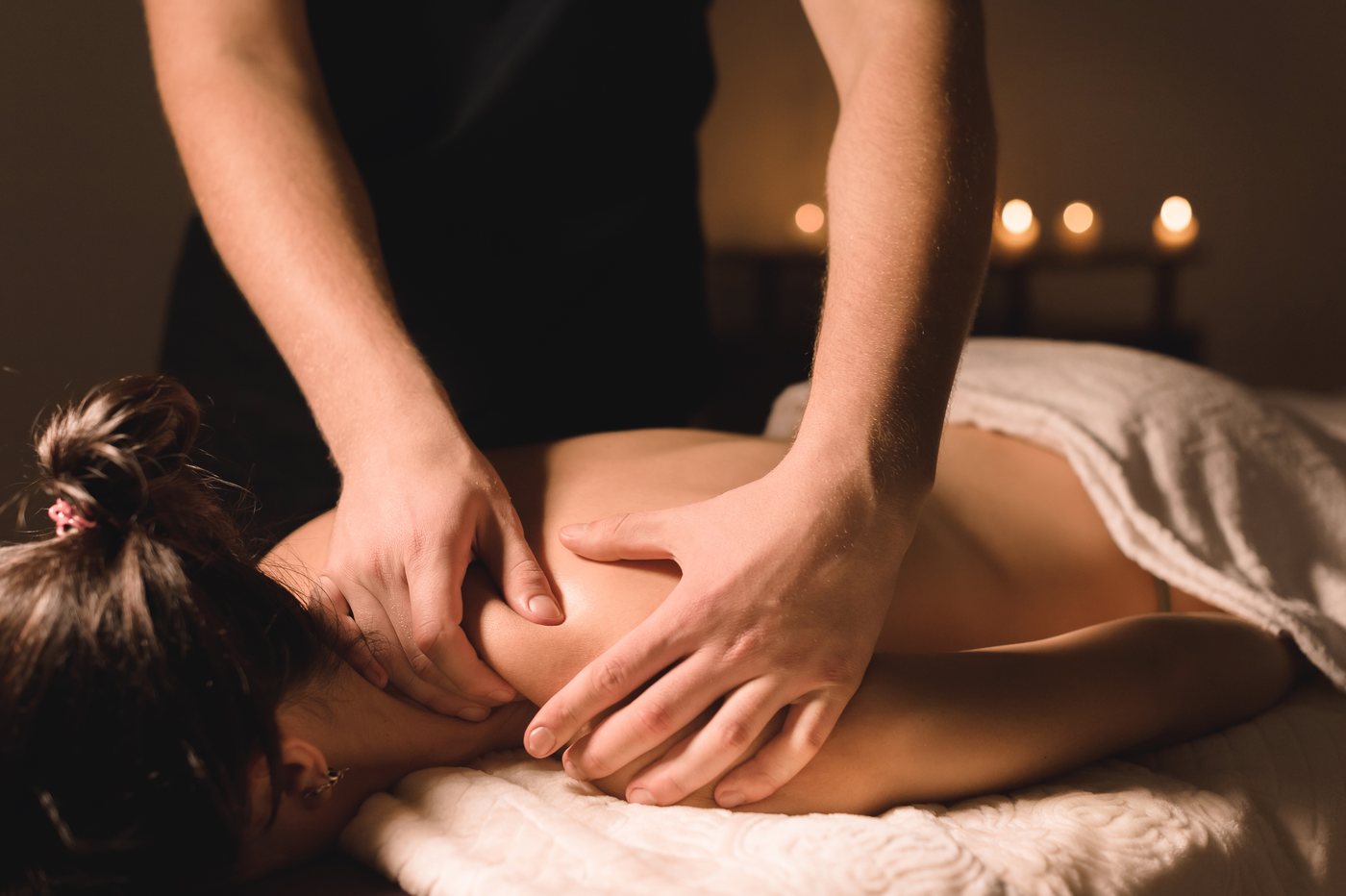 Warm-oil Abhyanga massage being performed on a client's back by candlelight