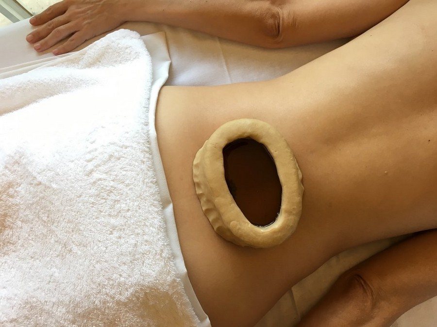 Warm oil held within a dough ring on a client's lower body
