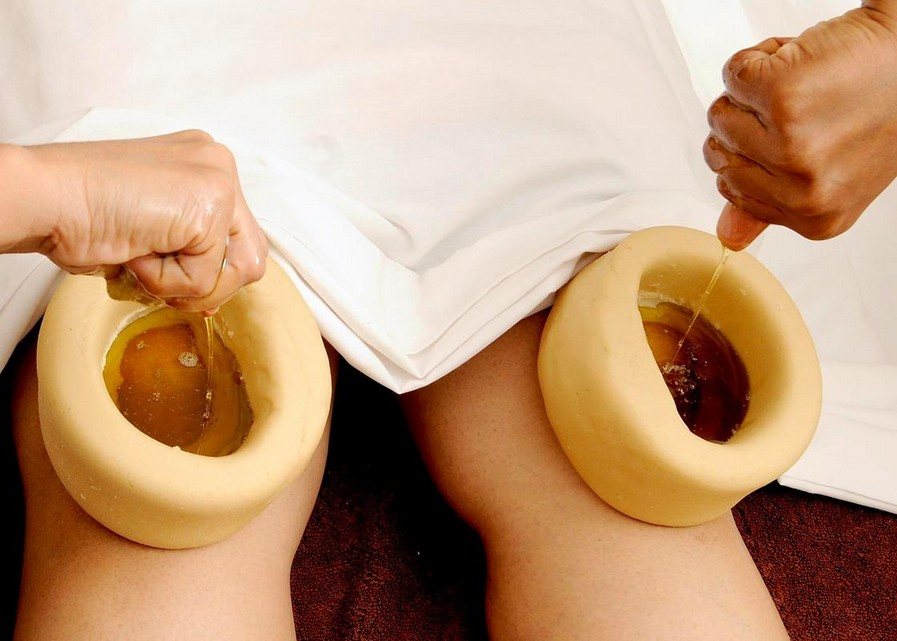 Two dough wells filled with warm herbal oil placed over a client's knees